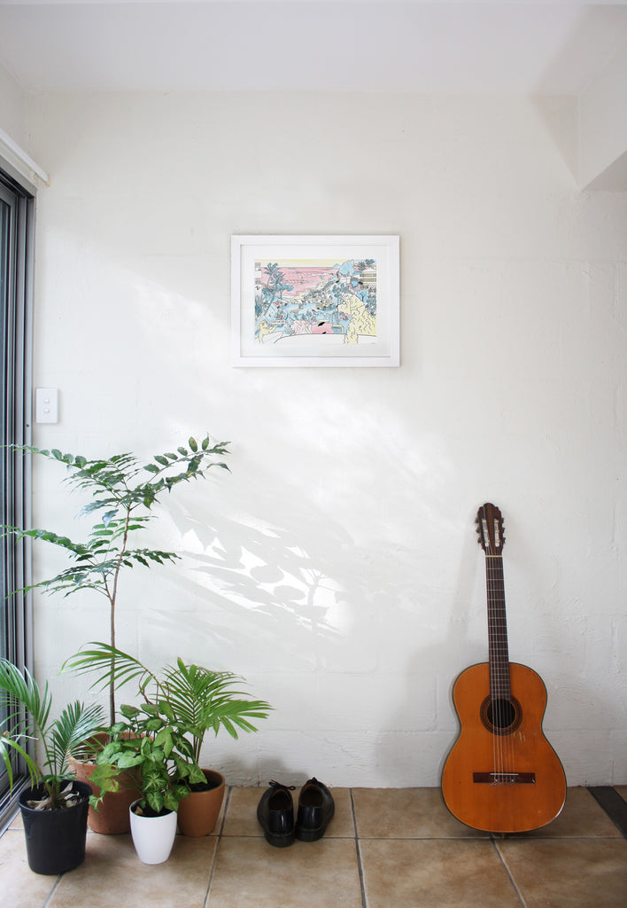 Wategos framed artwork on a white wall in apartment with pot plants and acoustic guitar