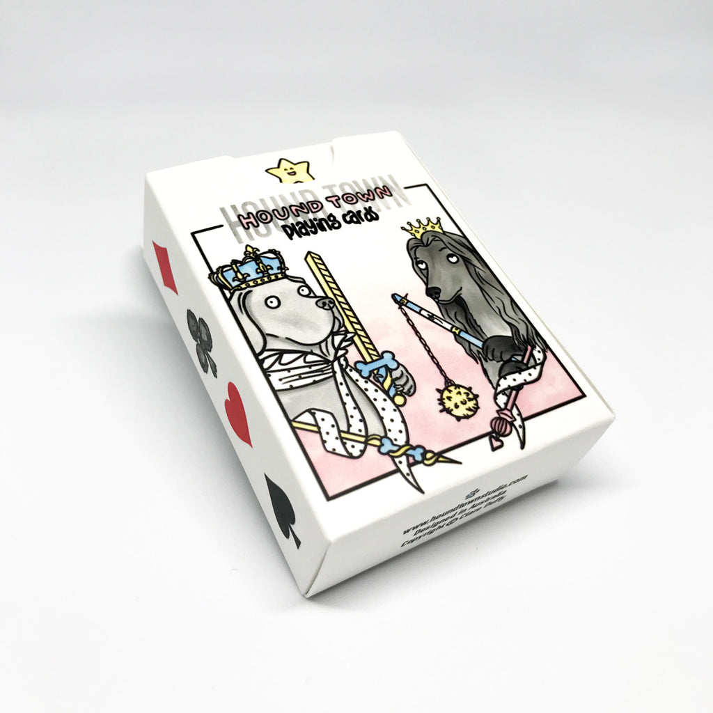 The packaging for Clare Duffy artist Hound Town playing cards, in pastel pink blue yellow and greys - featuring the Weimaraner holding a sword and an Afghan Hound holding a mace ball and chain, there is also a diamond, club, heart and spade symbol on the side of the box.