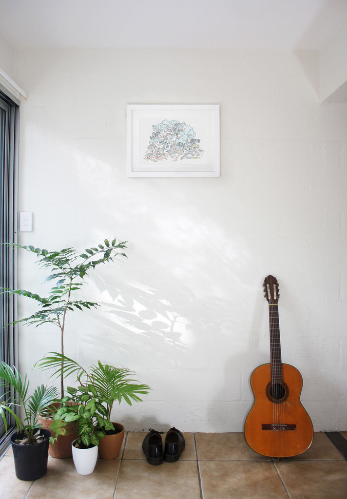 Doorway of an apartment with plants, doc marten shoes, a guitar and a Hound Town artwork framed on a white wall.